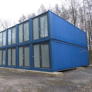Blaue Unterkunft/Container für Geflüchtete Flüchtlinge in Odenthal stehen auf einem Parkplatz am Wald.&nbsp;