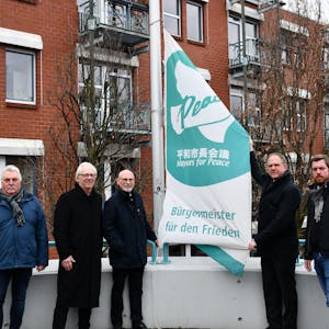 Das Foto zeigt, wie unter anderem Hürths Bürgermeister Dirk Breuer die „Mayors for Peace“-Flagge hisst.