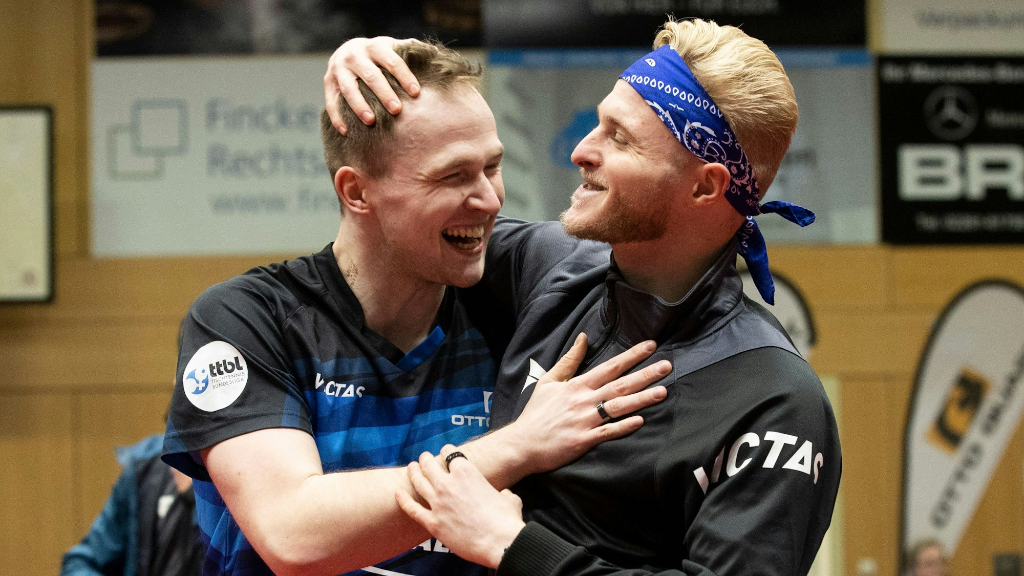 Zwei Tischtennisspieler liegen sich lachend in den Armen.