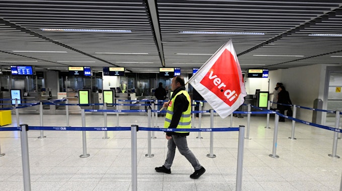 Mann mit Verdi-Fahne geht durch den Flughafen in Düsseldorf.