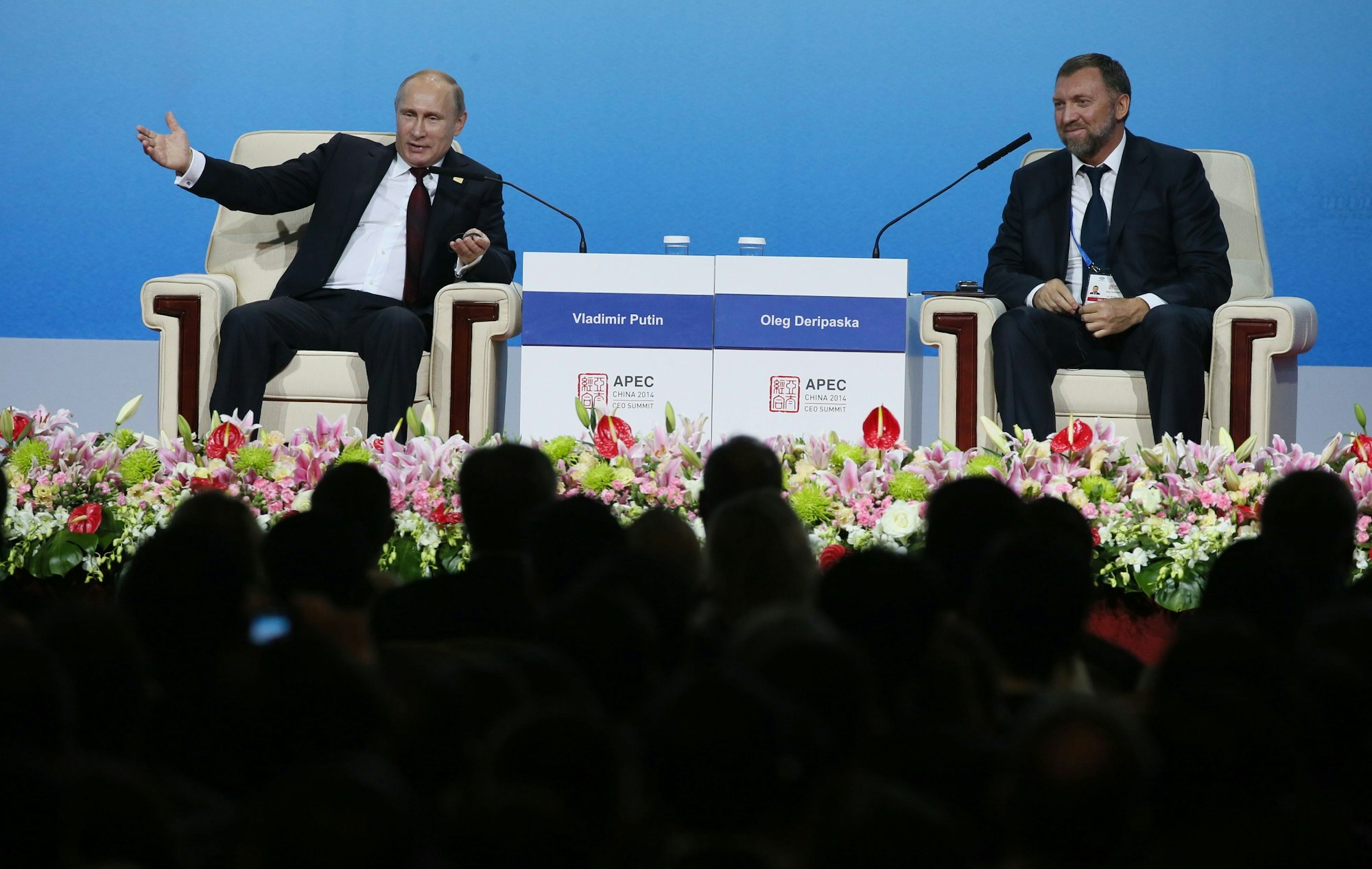 Der russische Oligarchen Oleg Deripaska (r.) sitzt gemeinsam mit dem russischen Präsidenten Wladimir Putin (l.) auf einer Bühne.