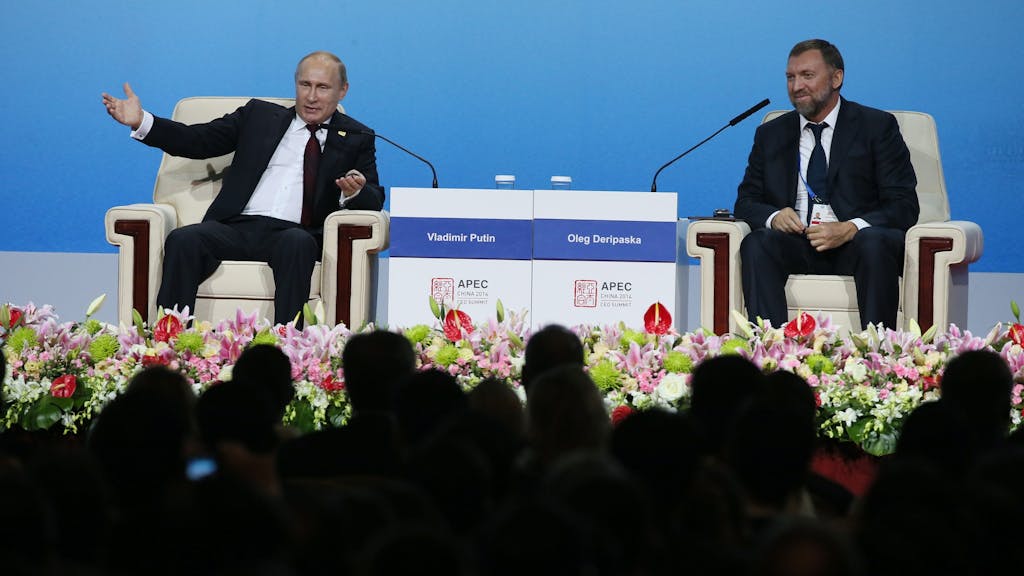 Der russische Oligarchen Oleg Deripaska (r.) sitzt gemeinsam mit dem russischen Präsidenten Wladimir Putin (l.) auf einer Bühne.&nbsp;