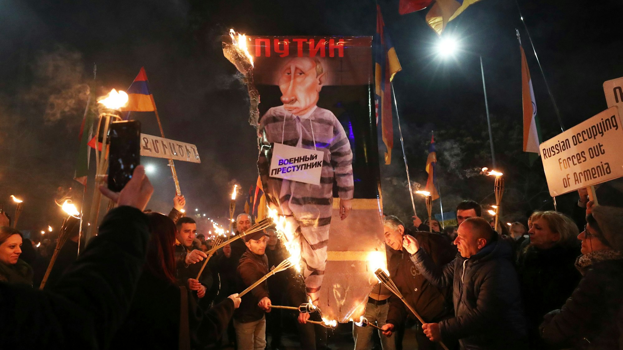 Menschen verbrennen ein Anti-Putin-Plakat mit der Aufschrift «Kriegsverbrecher» während einer Kundgebung zum ersten Jahrestag der russischen Invasion in der Ukraine. Die russische Armee hatte die Ukraine am 24.02.2022 überfallen. +++ dpa-Bildfunk +++