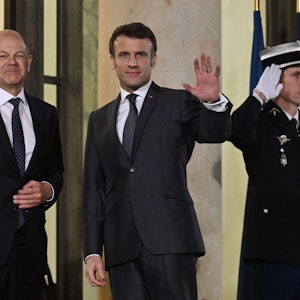 Emmanuel Macron (r.), Präsident von Frankreich, und Bundeskanzler Olaf Scholz (l, SPD) stehen vor einem Treffen mit dem ukrainischen Präsidenten im Elysee-Palast zusammen.