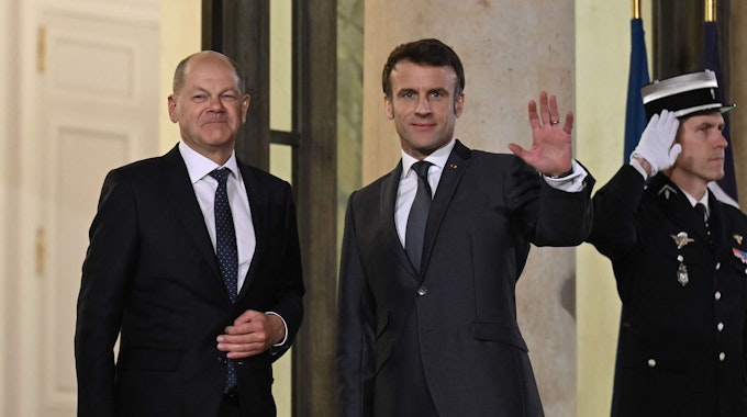 Emmanuel Macron (r.), Präsident von Frankreich, und Bundeskanzler Olaf Scholz (l, SPD) stehen vor einem Treffen mit dem ukrainischen Präsidenten im Elysee-Palast zusammen.