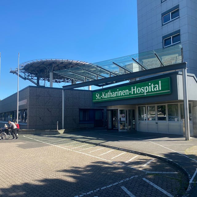Das Foto zeigt den Eingangsbereich des Frechener Krankenhauses von außen. In weißer Schrift auf grünem Grund steht „St.-Katharina-Hospital“.
