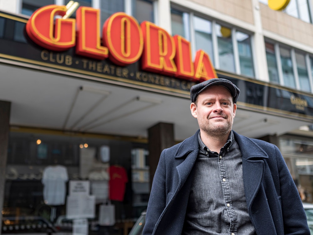 Komiker Max Giermann steht vor dem Gloria in Köln und lacht in die Kamera.