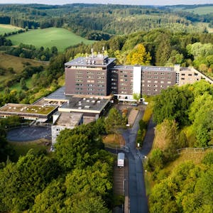 Das große Gebäude der früheren Eifelhöhen-Klinik in Marmagen, die jetzt als Unterkunft für Geflüchtete genutzt wird, liegt am Ortsrand von Marmagen und ist von idyllischer Natur umgeben.