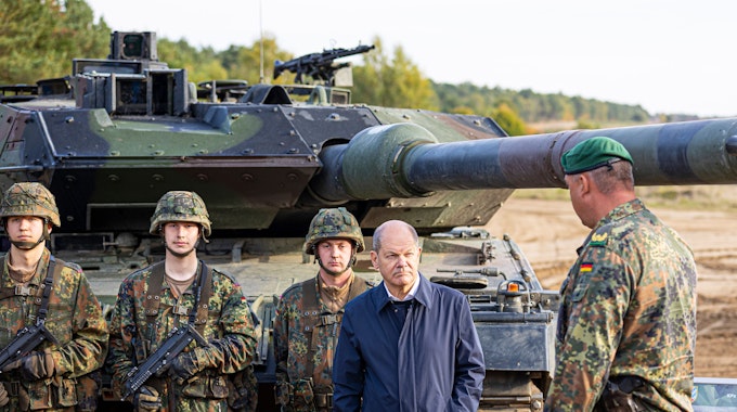 Bundeskanzler Olaf Scholz (SPD, 2.v.r) lässt sich vor der Ausbildungs- und Lehrübung des Heeres im Landkreis Heidekreis in der Lüneburger Heide den Kampfpanzer „Leopard 2“ der Bundeswehr erklären.
