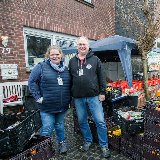 Mareike Berchem und Andreas Prinz stehen zwischen Kister voller Obst und Gemüse.