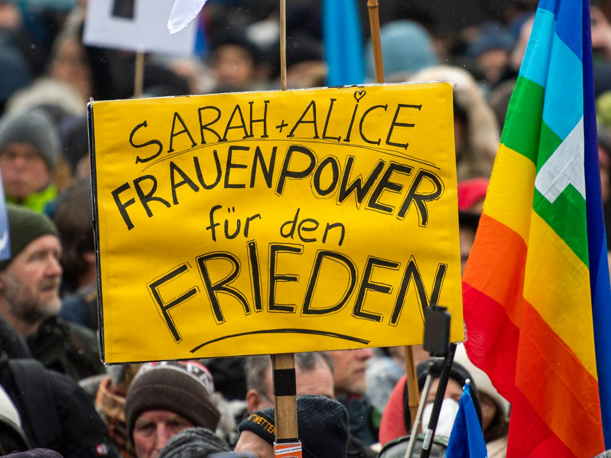 Ein Teilnehmer einer Demonstration für Verhandlungen mit Russland am Brandenburger Tor hält ein Plakat mit der Aufschrift „Sarah + Alice - Frauenpower für den Frieden“.