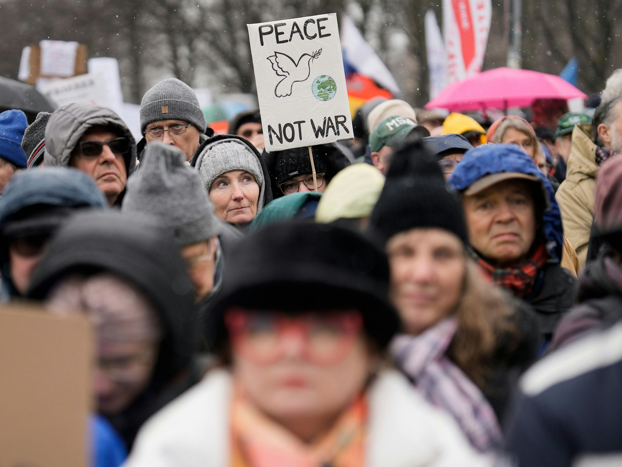Ein Teilnehmer hält ein Plakat hoch mit der Aufschrift „Peace not War“.