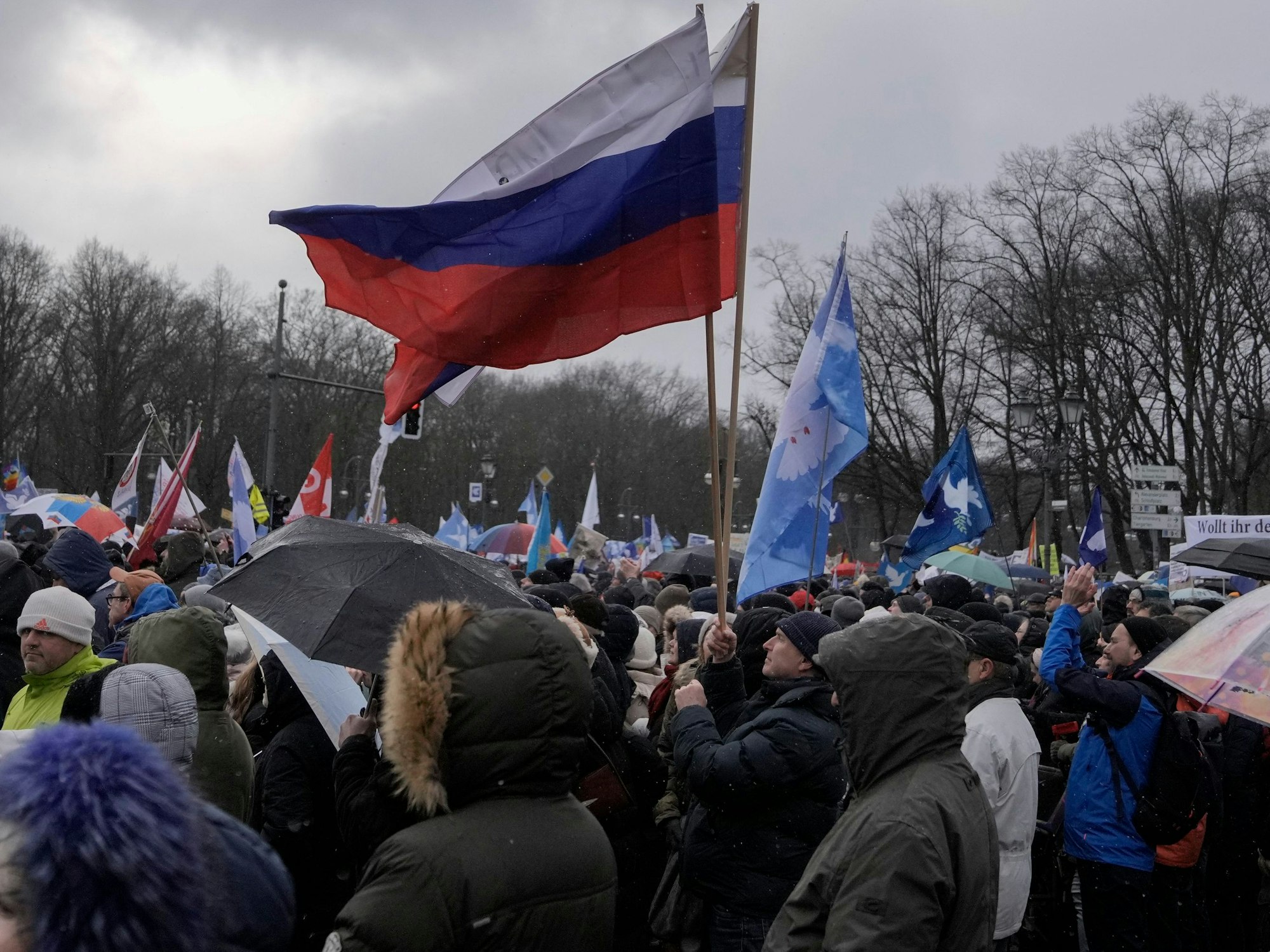 Ein Mann hat russische Flaggen in der Hand.