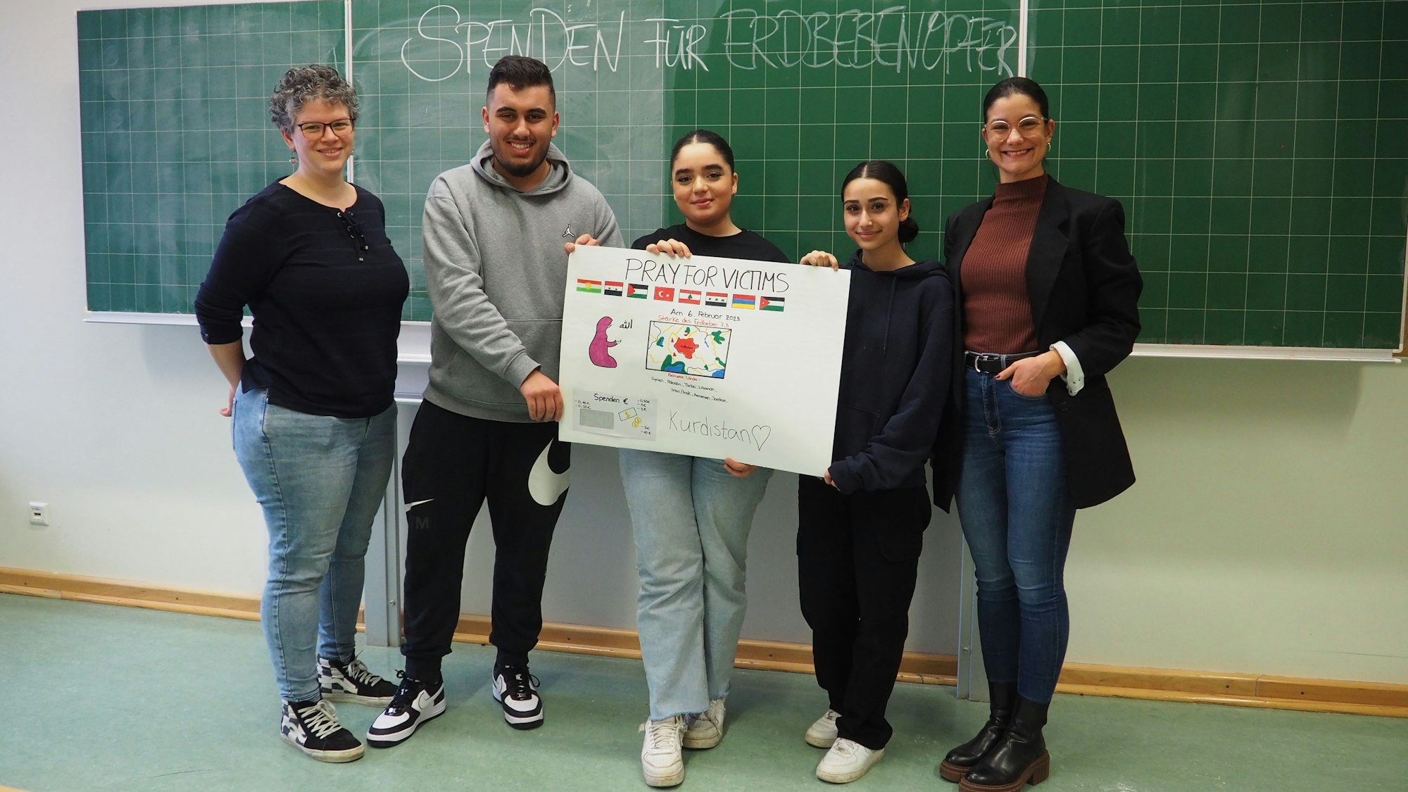 Die Schüler und Lehrer der Leverkusener Gesamtschule halten ein Plakat ihres Kuchenverkaufs vor.