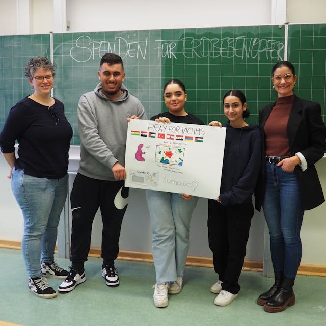 Die Schüler und Lehrer der Leverkusener Gesamtschule halten ein Plakat ihres Kuchenverkaufs vor.