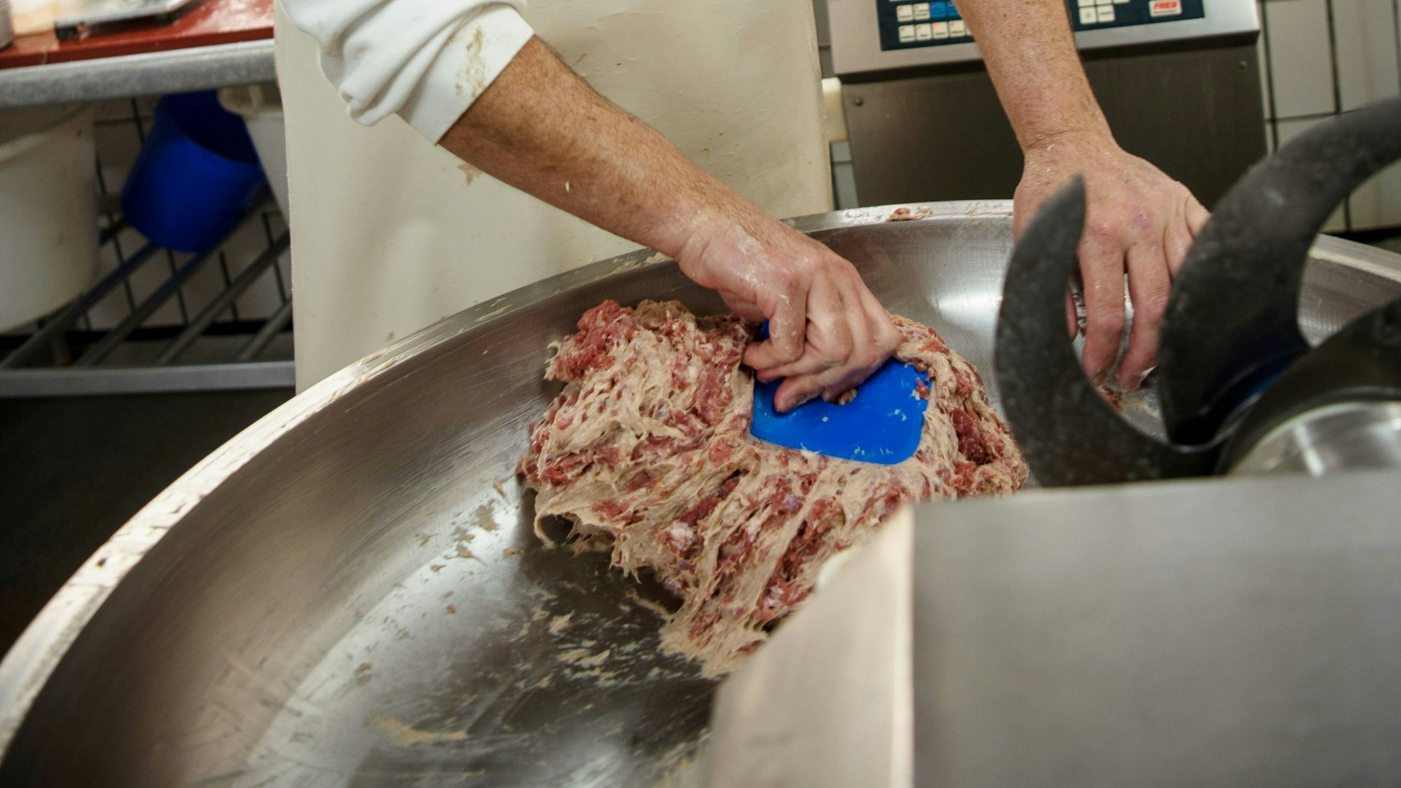 Es ist das Fleisch in einer Maschine zu sehen, dass vom Metzger bearbeitet wird.