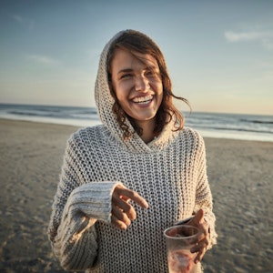 Junge Frau am Strand schaut glücklich drein.