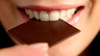 Eine Frau beißt in ein Täfelchen Schokolade.