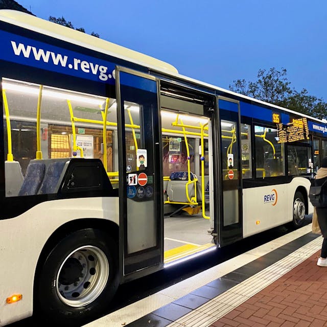 Ein Bus steht mit offenen Türen an einer Haltestelle.