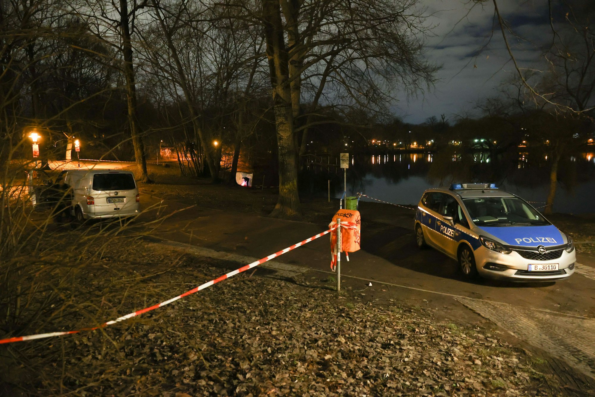 Fahrzeuge der Polizei stehen am Ufer des Weißen Sees in Berlin-Pankow. Am Ufer des Sees wurden zwei Leichen gefunden. Es soll sich um eine Frau und ein Kleinkind handeln, teilte die Polizei mit.