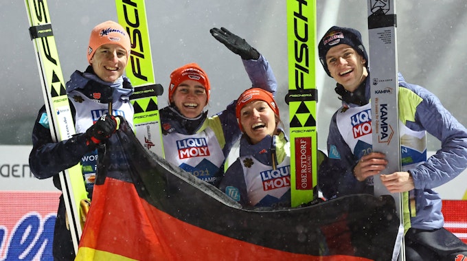 Karl Geiger, Selina Freitag, Katharina Althaus, Andreas Wellinger aus Deutschland jubeln nach Gold im Mixed-Wettbewerb.