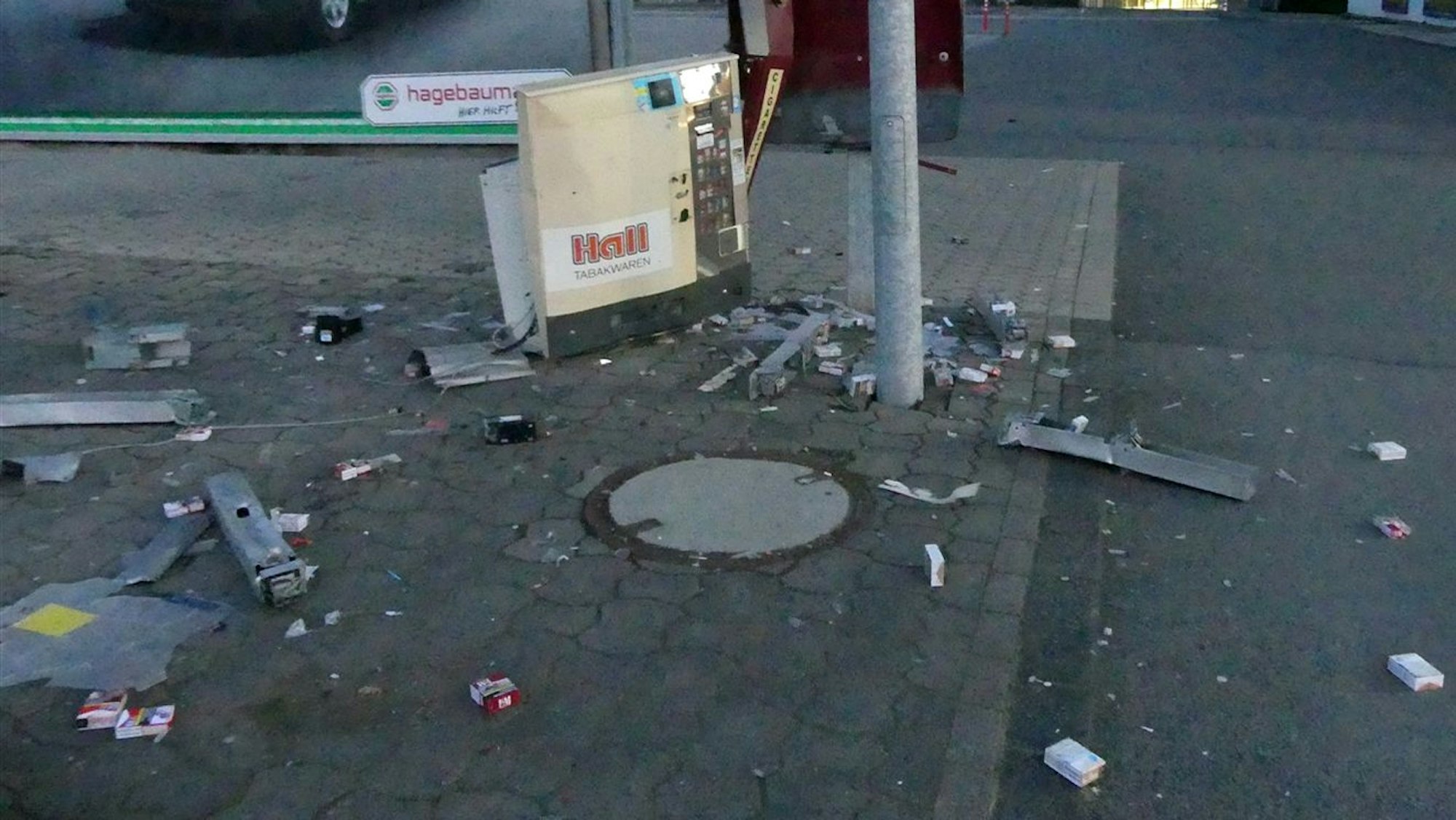 Teile eines in die Luft gesprengten Zigarettenautomaten liegen auf einer Straße verteilt.