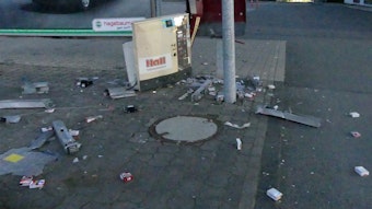 Teile eines in die Luft gesprengten Zigarettenautomaten liegen auf einer Straße verteilt.