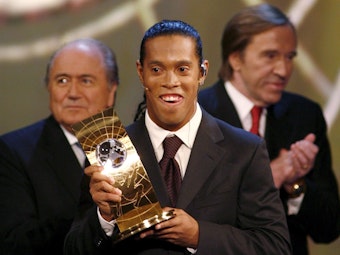 Ronaldinho posiert mit seinem Weltfußballer-Award, im Hintergrund sind Sepp Blatter und Günter Netzer zu sehen.
