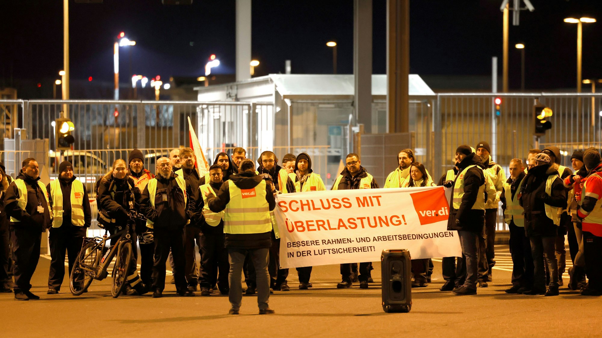 Streikende inWarnkleidung halten ein Banner der Gewerkschaft Verdi mit der Aufschrift: „Schluss mit Überlastung!“.