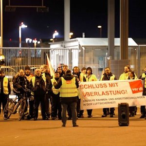 Streikende in Warnkleidung halten ein Banner der Gewerkschaft Verdi mit der Aufschrift: „Schluss mit Überlastung!“.