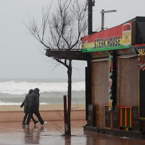 Ein Paar geht bei stürmischem Wetter an der Strandpromenade von Can Picafort spazieren. Für die nächsten Tage wird Regen mit niedrigen Temperaturen erwartet.