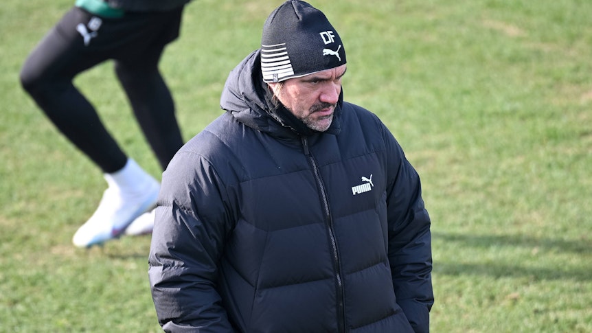 Daniel Farke, Trainer von Borussia Mönchengladbach, hier bei einer Trainingseinheit der Fohlen am 9. Februar 2023. Der Coach ist ganz in Schwarz gekleidet, trägt eine Mütze und schaut grimmig in die Ferne.