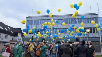 Bei einer Friedensdemo in Lohmar lassen Demonstranten gelbe und blaue Luftballons aufsteigen.