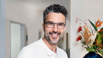 Christian Levejohann ist Zahnarzt in Köln und „wir helfen“-Unterstützer, er hat graumelierte Locken einen graumelierten Bart und trägt eine schwarze Brille.