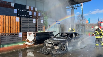 Ein Feuerwehrmann löscht ein brennendes Auto.