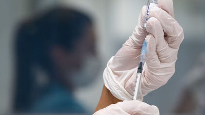 ARCHIV - 25.11.2021, Baden-Württemberg, Gerlingen: Eine Frau zieht eine Dosis des Impfstoffes von Biontech/Pfizer für eine Corona-Impfung auf.