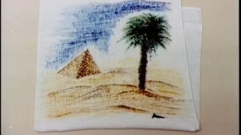 Ein weißes Badetuch mit dem Motiv einer Palme und einer Pyramide