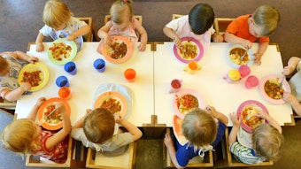 Kinder sitzen in einer Kindertageseinrichtung in Leipzig beim Mittagessen.