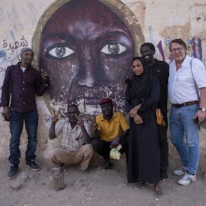 Hans Mörtter (r.) und Hassan Magdi (l.) mit anderen in Khartum vor einem Wandbild, das die 2012 erschossene Parlamentarierin Awasia Ajbna zeigt.