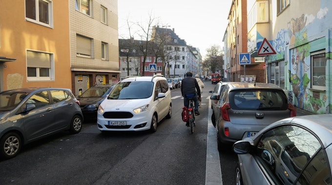 Ein Auto und zwei Radfahrer, die sich auf einer engen Straße entgegenkommen