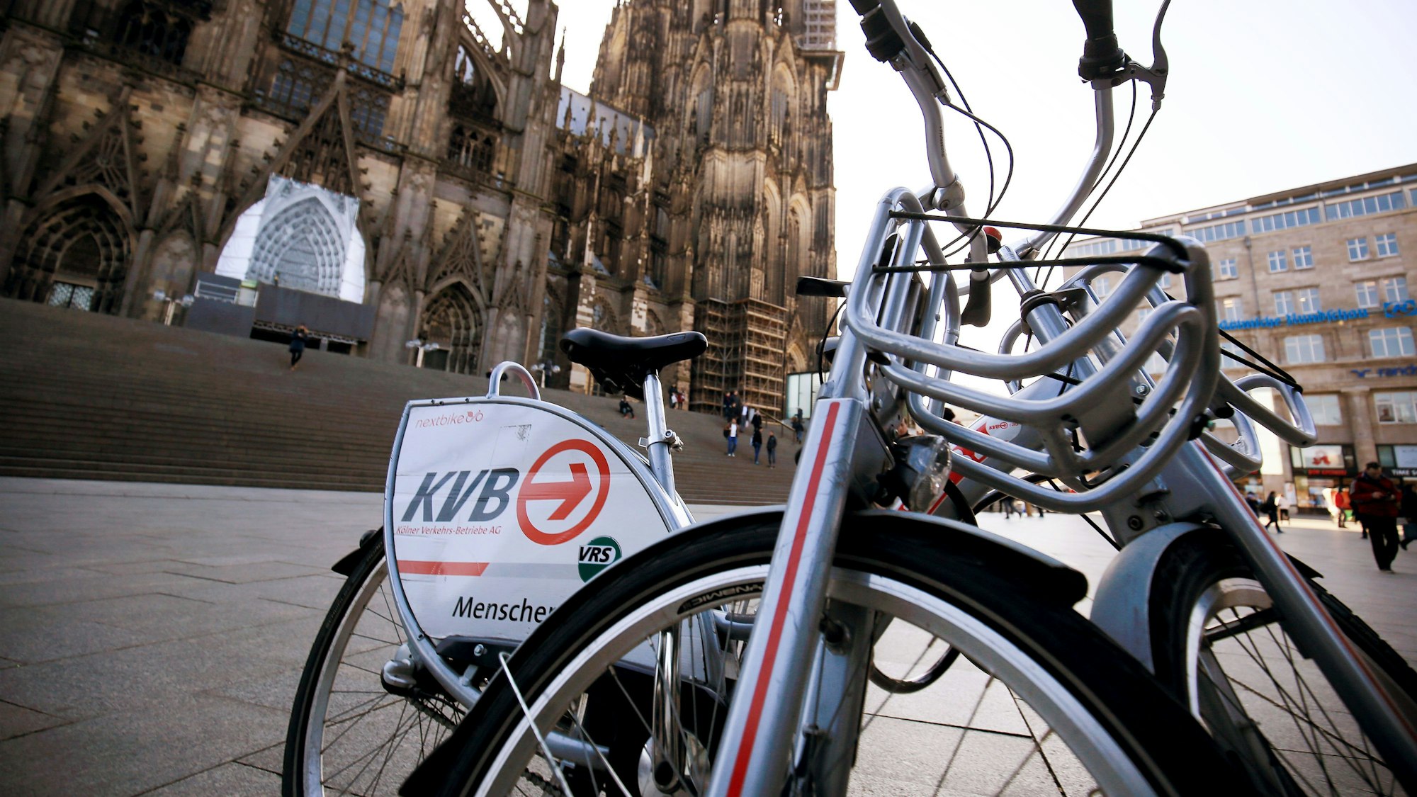ARCHIV - Ein Leihfahrräder der Kölner Verkehrs-Betriebe (KVB) stehen am 13.02.2017 in Köln (Nordrhein-Westfalen) vor dem Dom.
