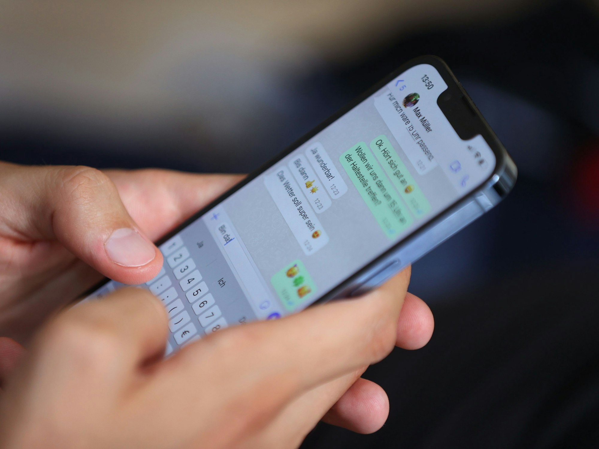 Ein junger Mann tippt auf einem Smartphone eine WhatsApp-Nachricht.