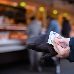 Eine Frau steht an einem Stand an und hält das Bargeld für ihren Einkauf in der Hand bereit.