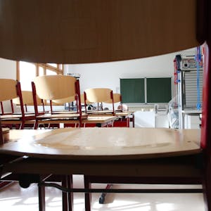 Leere Stühle stehen auf den Pulten einer leeren Klasse.