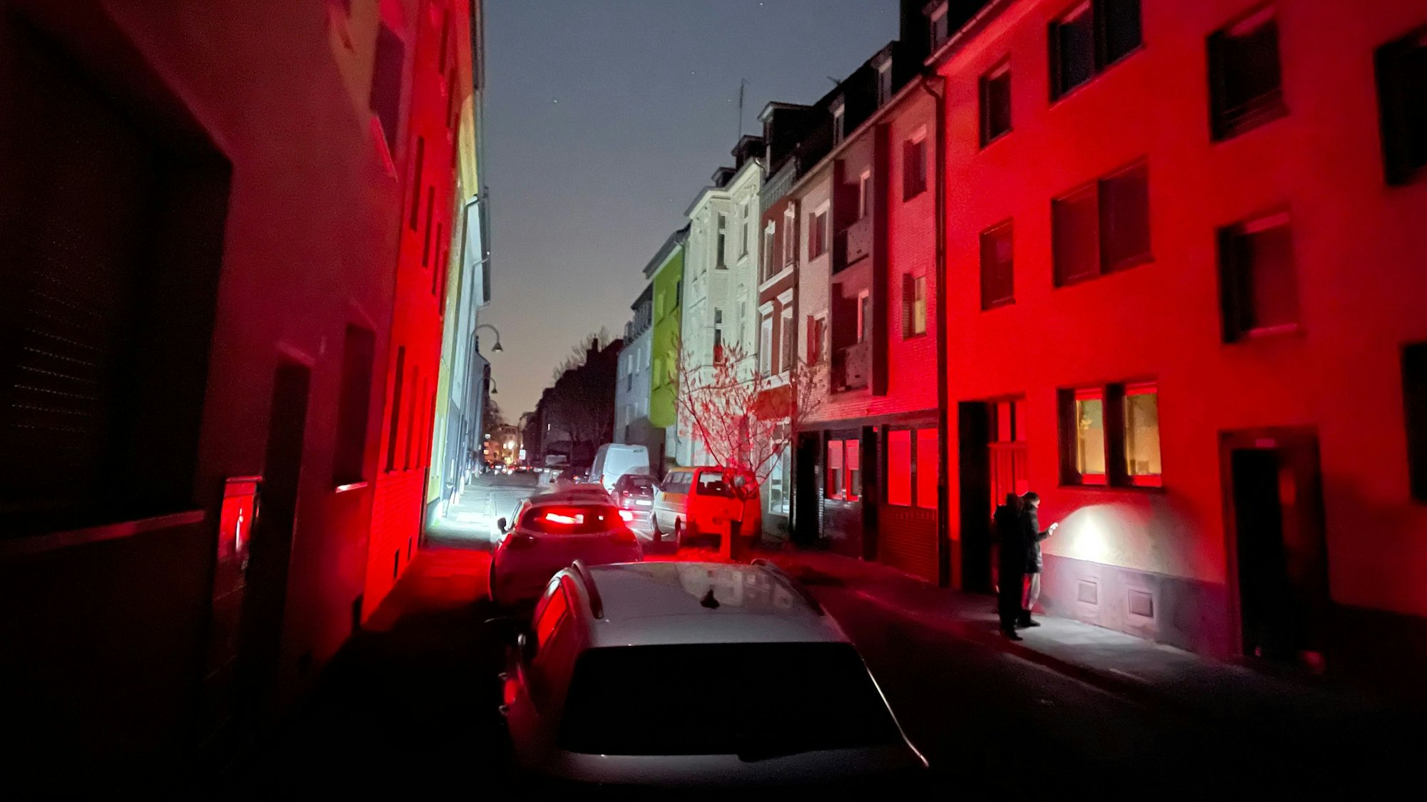 Stromausfall in Köln-Mülheim: Eine Straße ist dunkel, Licht gibt es nur von Autos und Taschenlampen.