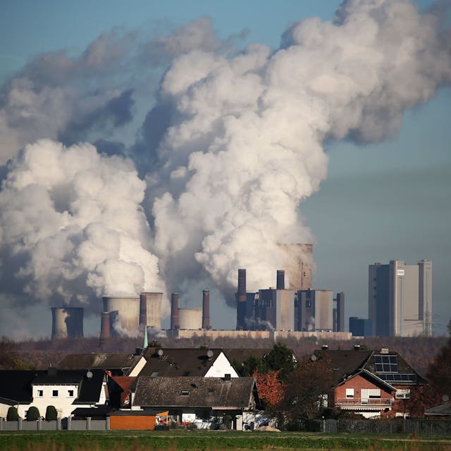 Hinter einer Wohnsiedlung bei Bergheim steigt Dampf aus dem Braunkohlekraftwerk Niederaußem des Energieversorgungskonzerns RWE.