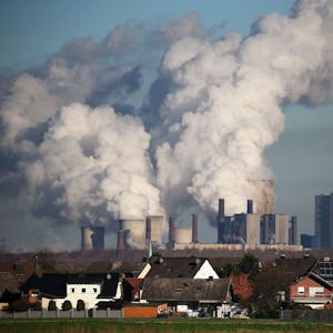 Hinter einer Wohnsiedlung bei Bergheim steigt Dampf aus dem Braunkohlekraftwerk Niederaußem des Energieversorgungskonzerns RWE.