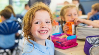 Smiling school students in uniform missing a tooth with a healthy sandwich for lunch, Foto: Getty Images/davidf