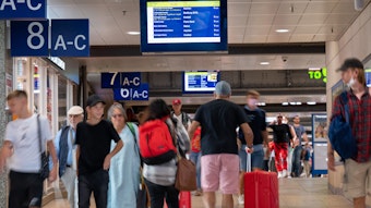 Reisende suchen nach Informationen auf den Anzeigetafeln im Kölner Hauptbahnhof. Links sind Schilder der einzelnen Gleise zu sehen. (Symbolbild)