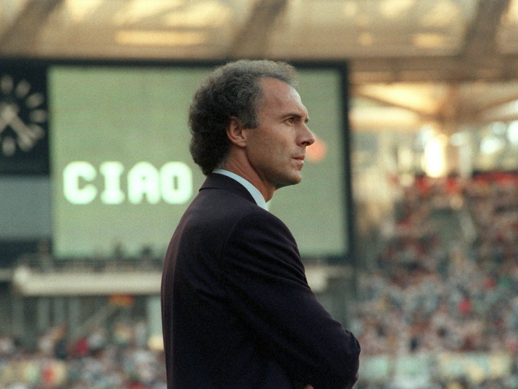 Franz Beckenbauer, damals DFB-Teamchef, schaut mit ernstem Gesicht auf das Spielfeld des Olympiastadions.